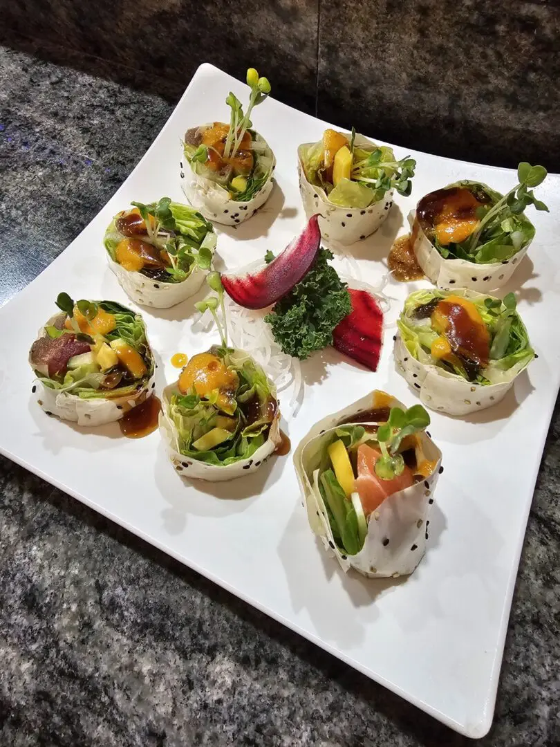 A white plate topped with sushi covered in vegetables.